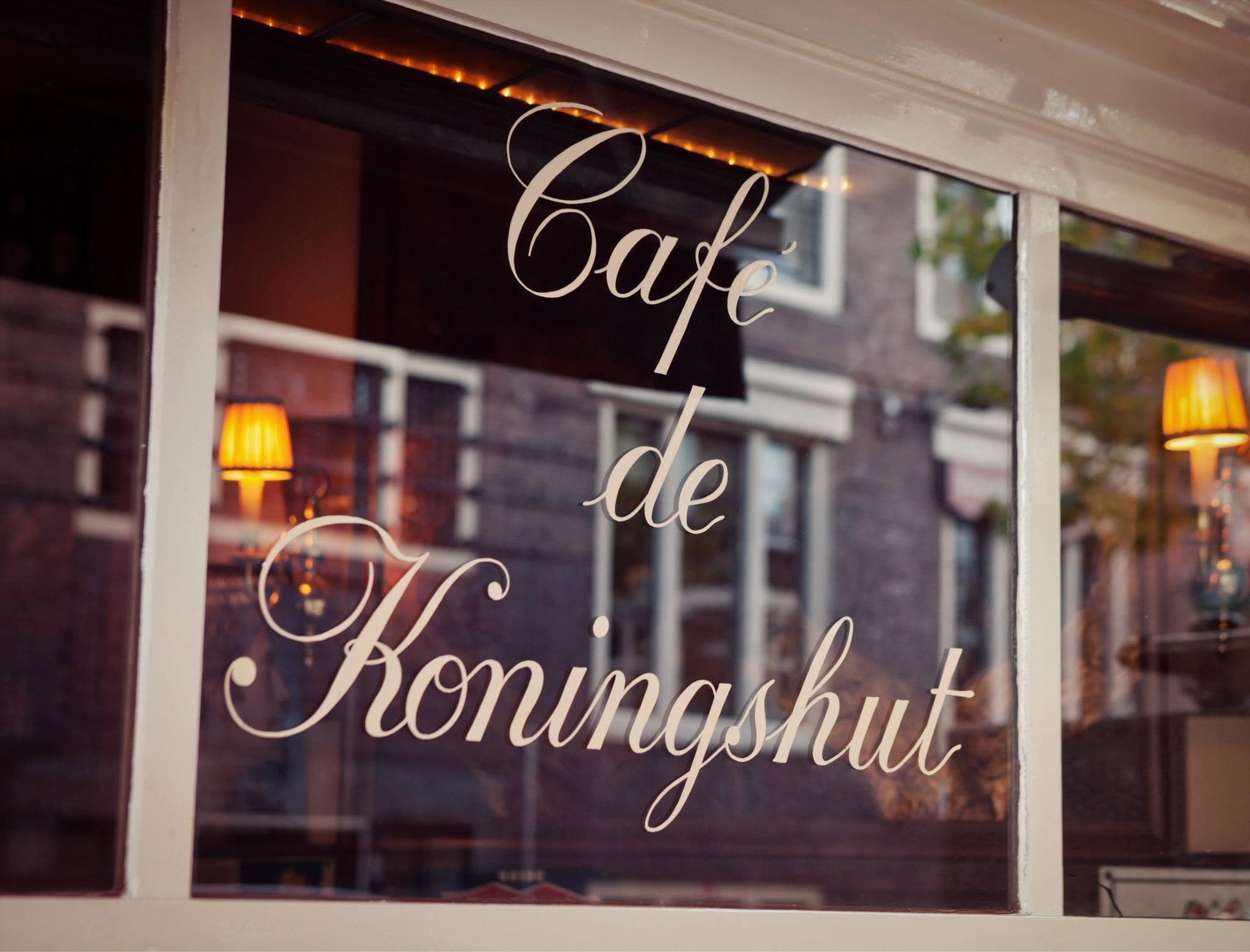 De naam Café de Koningshut in sierlijke letters op het gevelraam